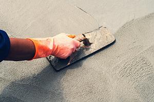 construction worker spreading wet concrete by hand