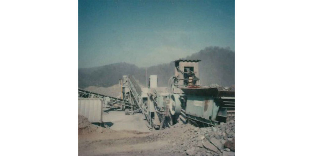 older image of a cone crusher on a site